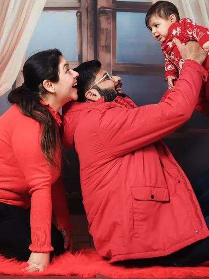 A playful family photo from a Christmas session, with parents lifting their baby in the air.