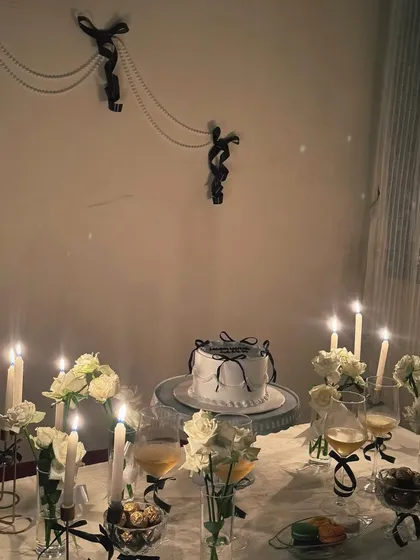 A closer look at our black and white themed table. This aesthetic is achieved with white roses, black ribbon details on the cake and glassware, and the soft, romantic light of tapered candles.