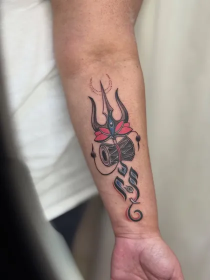 A clear, bright photo of the finished Trishul and Ganesha forearm tattoo.