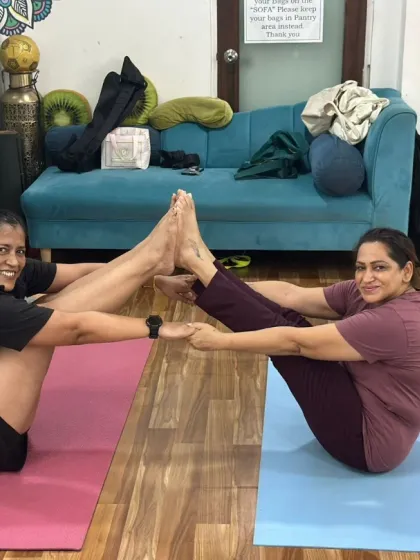 Two practitioners find balance and connection in this seated partner pose, a perfect example of the community spirit at our studio.