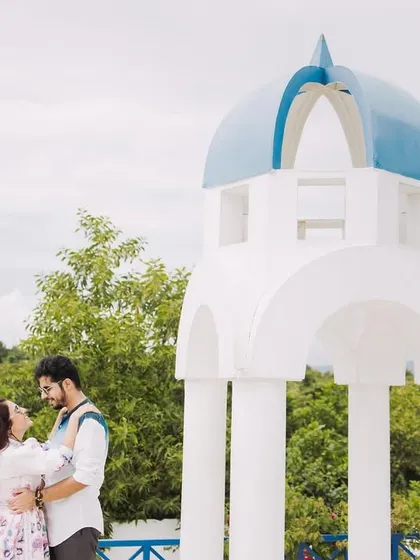 A classic couple pose against a Greek-style gazebo. The clean lines and natural background create a fresh and romantic pre-wedding photo.