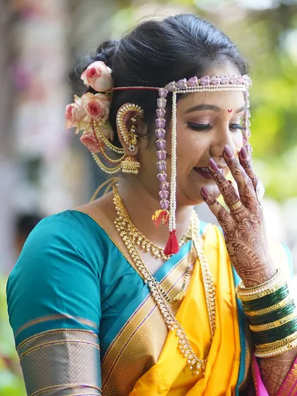 A candid, shy smile from the bride. This photo captures the soft, romantic feel of the makeup and the delicate flower arrangement in her hair.
