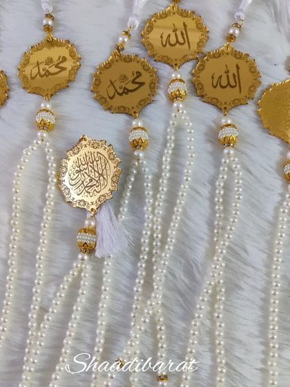 A collection of custom Tasbeeh favors. These feature pearl-like beads and gold acrylic charms with sacred inscriptions, making them a meaningful gift.