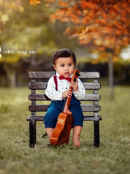 Sprinkling a little magic into childhood. An autumn-themed outdoor portrait of a little boy with his ukulele on a park bench.
