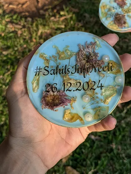 A single coaster from the pastel blue set, showing the detail of the preserved flowers, pearls, and custom text.