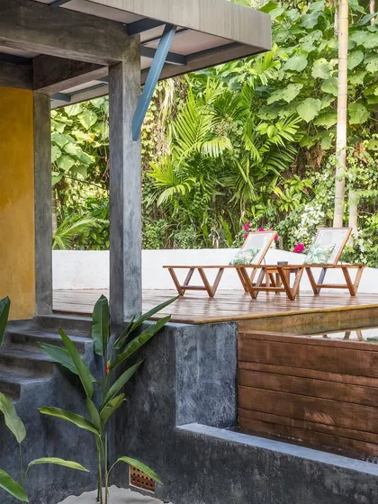 The deck of the private villa, furnished with comfortable lounge chairs for relaxing amidst the sounds of the forest. The space is designed to be a private outdoor retreat.
