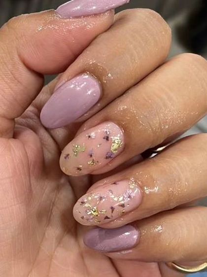 A close-up of the dried flower accent nails, paired with a solid mauve-purple polish on almond-shaped nails.