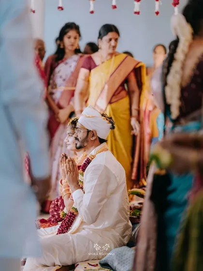 The couple in prayer during their wedding ceremony, surrounded by the warm presence of their family and friends.