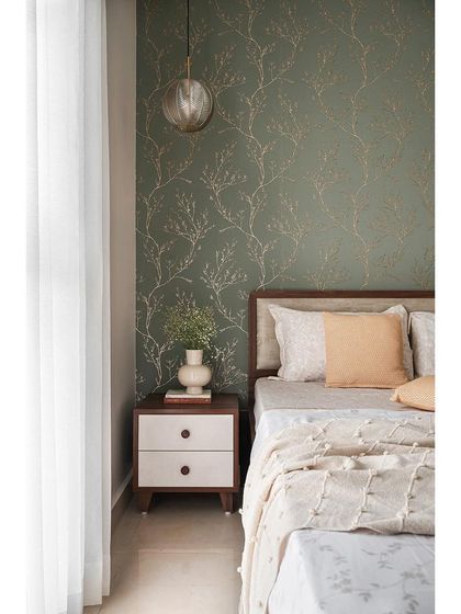 The bed in the parents' room is set against a classic olive green wallpaper with a delicate gold pattern. The simple, clean lines of the furniture allow the wallpaper to be the main feature.
