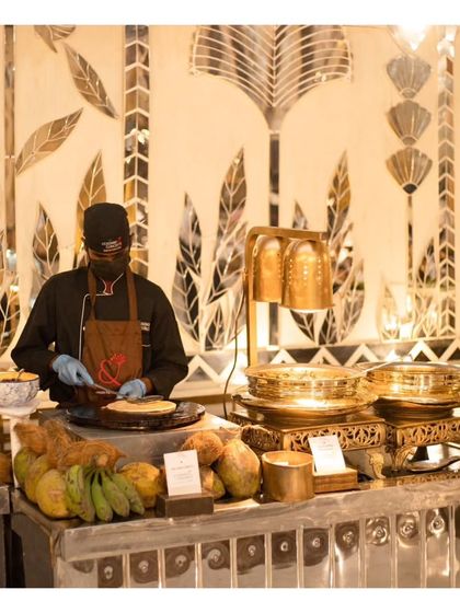 A chef preparing dishes at a live station set against an elegant, mirrored backdrop, showing how our setups can complement even the most luxurious decor.