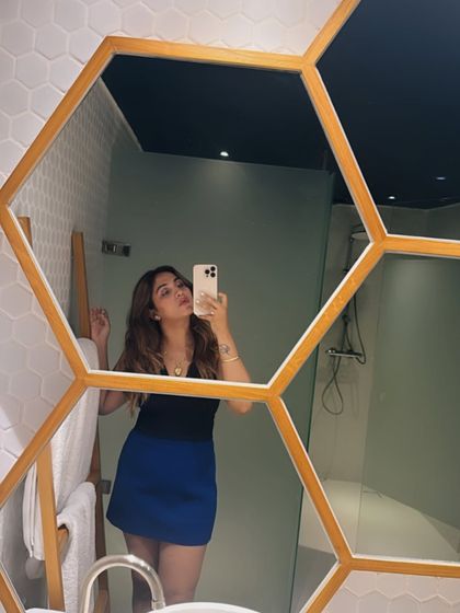 Here's the second vibe: a glam look. The same blue mini skirt is paired with a sleek black halter top and heels, transforming it into a sexy and sophisticated outfit for a night out.