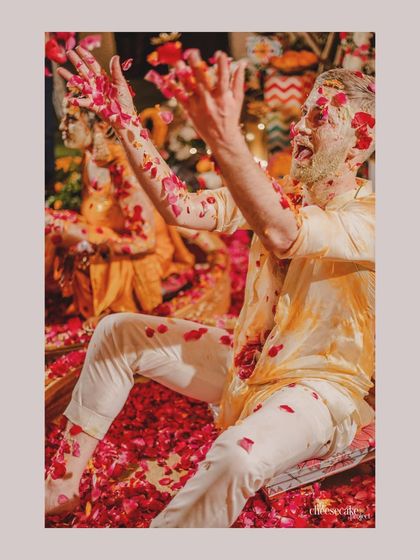 A candid moment of the groom mid-celebration, covered in petals and happiness.