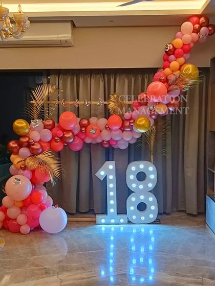 The warm tones of the balloons and the glow from the marquee numbers create a welcoming and celebratory ambiance in the room.