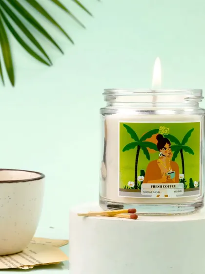 The playful label of this Irish Coffee candle is the star of this clean, modern setup. Paired with a simple ceramic cup and matches on a white pedestal, the image feels fresh, vibrant, and inviting.