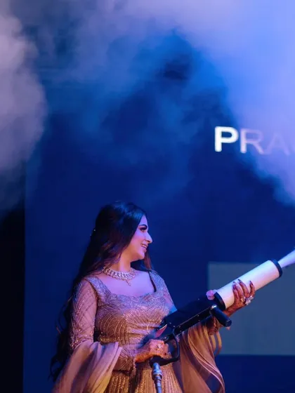 The bride, Nisha, takes center stage with a CO2 gun, her smile showing she's ready to party.