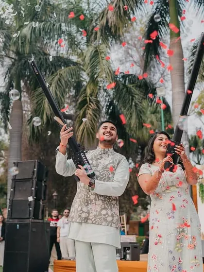 A fun, celebratory moment with the couple using confetti guns, showering their guests with petals and bubbles.