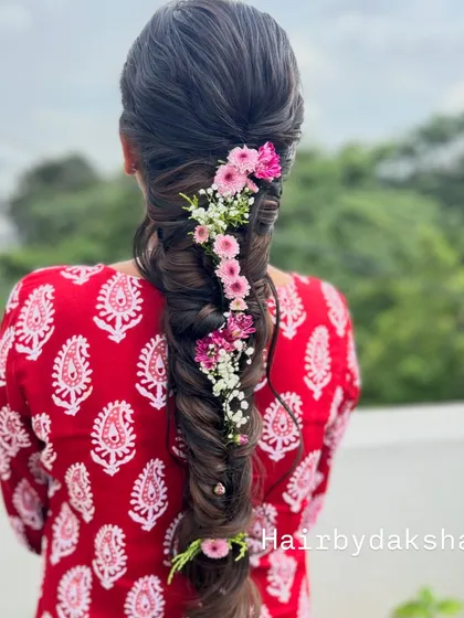 I love adding a touch of nature to my hairstyles. This thick, healthy fishtail braid is beautifully accented with a cascade of fresh pink and white flowers, creating a soft and romantic look for any wedding function.