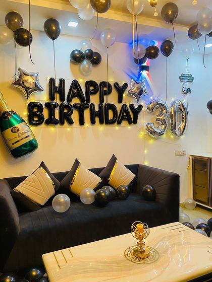 A sleek black and silver theme for a 30th birthday party. This setup includes black 'Happy Birthday' foils, a large '30' in silver, and a fun champagne bottle balloon.