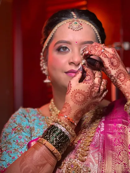 A candid shot of a bride getting ready for her wedding day. Her hair is styled in a traditional updo, providing a perfect base for her veil and jewellery.