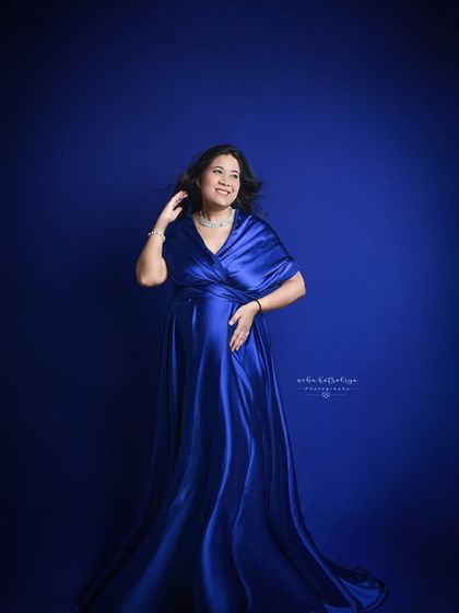 A full-length shot showcasing the elegance of this satin maternity gown. The way the fabric drapes beautifully highlights the baby bump.