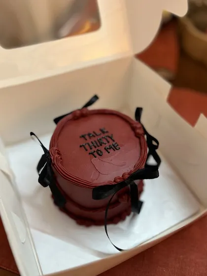 This deep red cake with the text "Talk Thirty To Me" is boxed up and ready to go. The black ribbons add a touch of drama to the design.