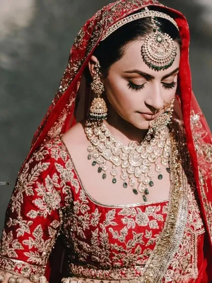 A detailed shot focusing on the bride's stunning makeup and heavy Polki and emerald jewelry.