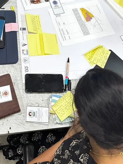 A top-down view of a workshop table, showing the tools of co-creation: architectural plans, identity cards for role-playing, and lots of sticky notes. This captures the organized chaos of a productive brainstorming session.
