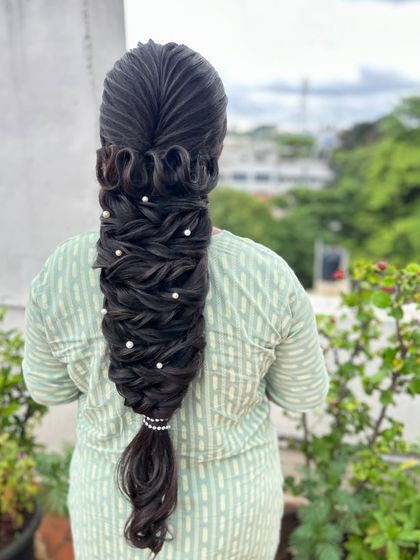 An intricate and highly technical braid with ribbon-like loops and pearl details, showcasing advanced hairstyling skills.