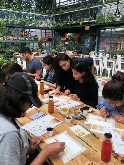 Guiding participants through the process of coffee painting. It's a hands-on experience where you learn techniques for creating different shades and effects.