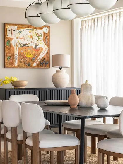 Another view of the dining area in Apartment 1600, highlighting the curated selection of furniture and art. The combination of the dark dining set, natural jute rug, and earthy ceramics creates a warm, inviting, and distinctly mid-century modern atmosphere.