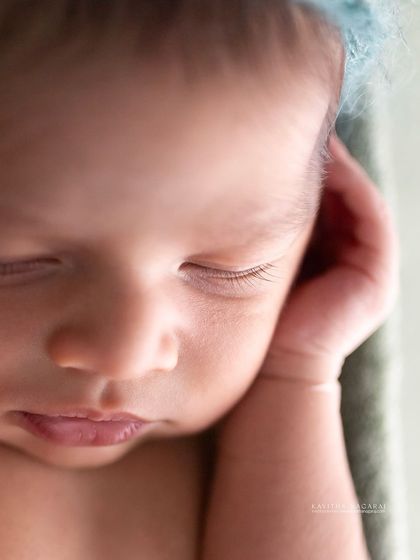 A black and white macro shot of a newborn's face. The close-up view reveals the delicate eyelashes and soft skin, details that fade too quickly.