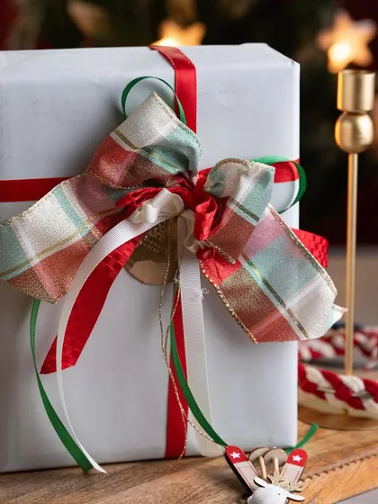 Another example of my gift wrapping, this time with a beautiful plaid bow and delicate red, white, and green ribbons for a classic Christmas feel.