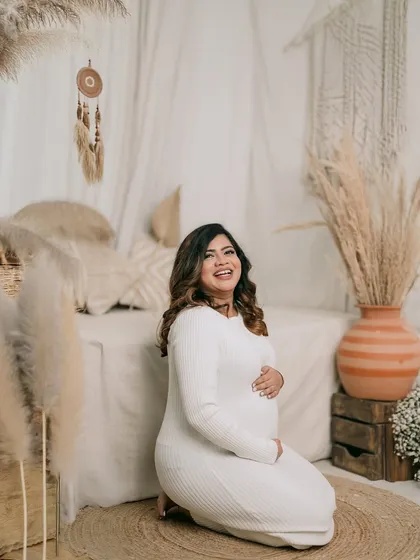 A joyful, candid shot of the expectant mother. Her radiant laugh and the way she cradles her bump perfectly capture the happiness of this special time.