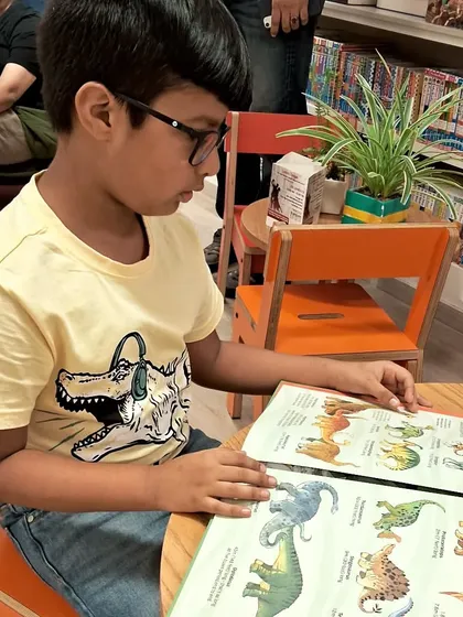A young reader completely absorbed in a book about dinosaurs. It's a joy to see curiosity sparked in our store.