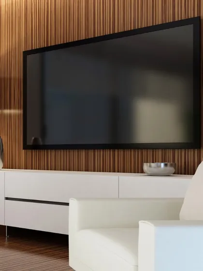 A perfect example of a modern media wall that blends seamlessly into the living room decor. The television is mounted on a rich, fluted wood panel, complemented by a minimalist white console that keeps the space feeling clean and uncluttered.