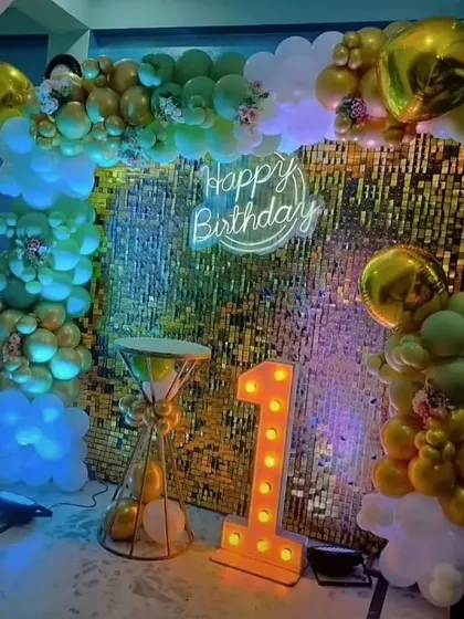 A first birthday party with a unique color scheme of green and gold against a sequin backdrop.