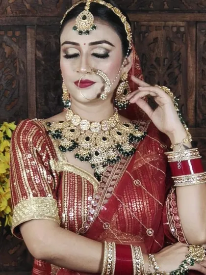 A close-up of the jewellery paired with the red gota patti lehenga. The set includes a choker, nath, maang tikka, and matching earrings.