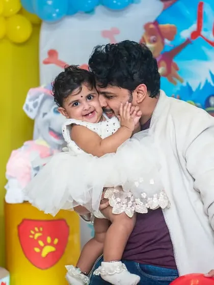 A father shares a sweet cuddle with his daughter during her Paw Patrol themed first birthday party.