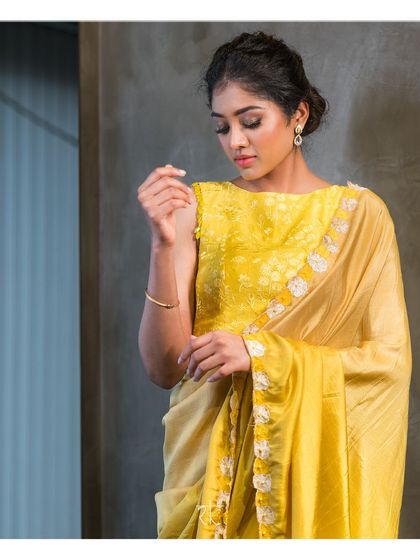 A graceful fusion of styles, this lime and ivory half and half saree is paired with an exquisitely embroidered blouse featuring self-thread work.