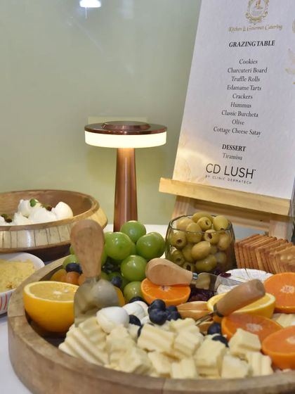Another view of the grazing board for the CD Lush event, showcasing the variety of cheeses, fruits, and olives, all beautifully arranged next to the custom menu.