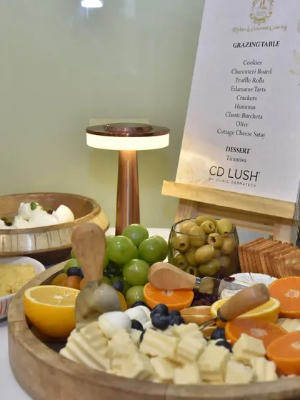 Another view of the grazing board for the CD Lush event, showcasing the variety of cheeses, fruits, and olives, all beautifully arranged next to the custom menu.