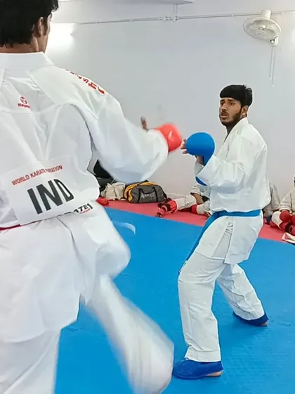 A student practices a kick during a kumite seminar, learning to apply techniques against a moving opponent.
