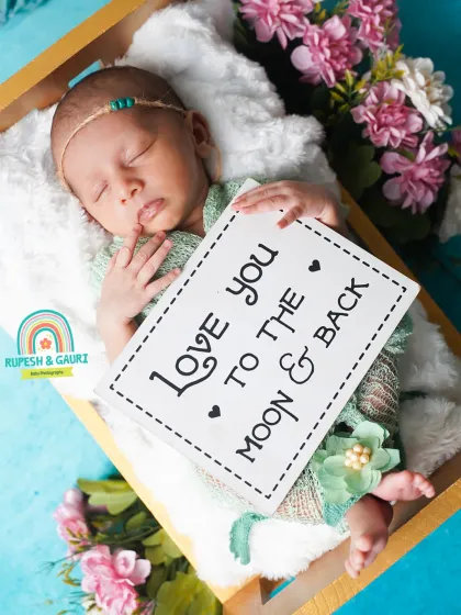 A close-up shot holding a sweet sign, "Love you to the moon & back." We use props like these to add a personal and heartfelt message to your baby's portraits.