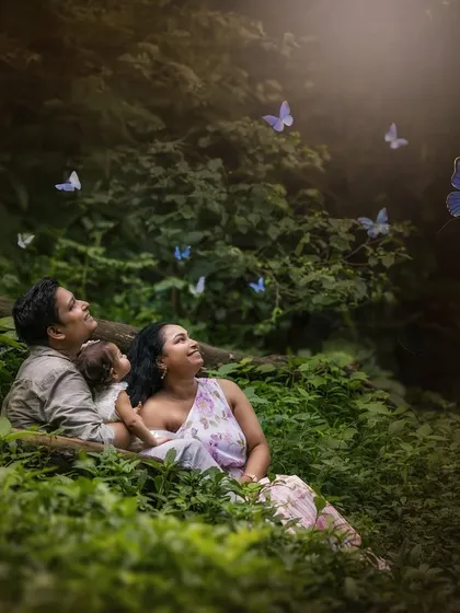 A family picnic with Mother Nature. This portrait captures a beautiful moment of connection as the family looks up at a swirl of blue butterflies in a dense, green forest.