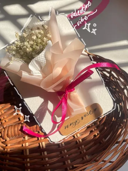A close-up of the wrapping on the mini bouquet. The layers of paper and the pink ribbon make it feel like a tiny, precious gift.
