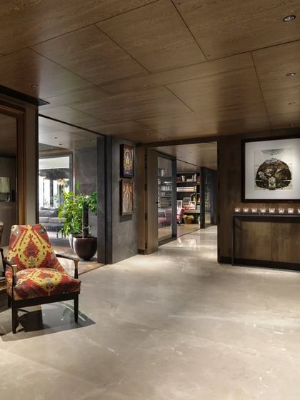 The entrance lobby of the Caitriona apartment, showcasing the complete transformation of the space. The warm wood veneers, rich stone, and curated art create an atmosphere of sophisticated and welcoming luxury.