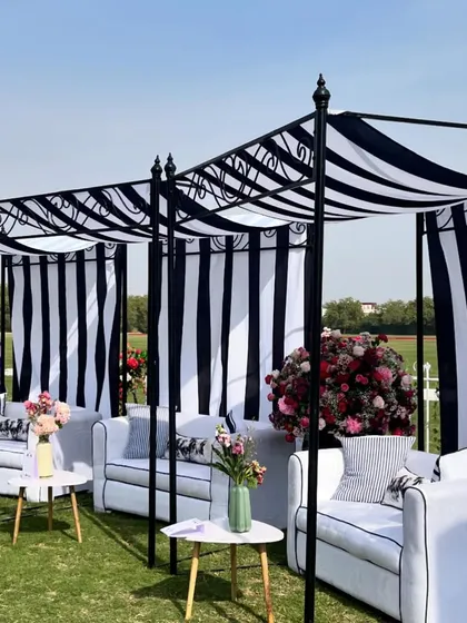 Chic black-and-white striped cabanas provided shaded seating for guests at the polo luncheon. The classic color scheme was accented with vibrant floral arrangements for a sophisticated look.