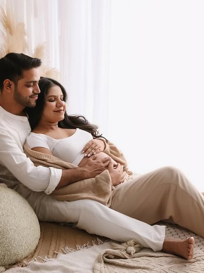 A cozy and intimate moment between the expecting parents, nestled together on our studio bed setup. The warm blanket and soft pillows create a feeling of home.