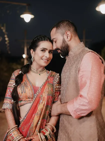 An intimate portrait from a carnival-themed wedding event. The warm lighting and the couple's close embrace create a romantic atmosphere amidst the vibrant celebration.
