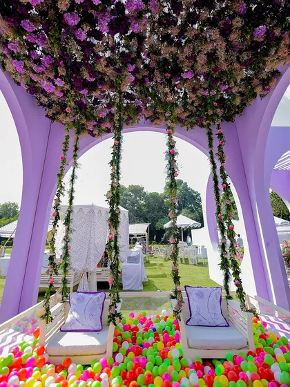 A playful and unique seating concept for the couple at their Haldi. A swing set adorned with a floral ceiling is placed over a pit of colorful balls, adding an element of fun and whimsy to the event.